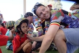 A man fits a bicycle helmet to a child.