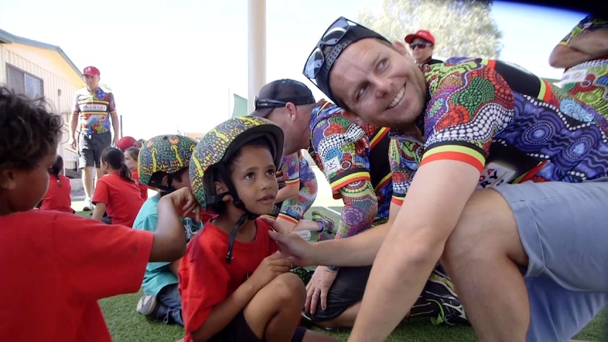 A man fits a bicycle helmet to a child.