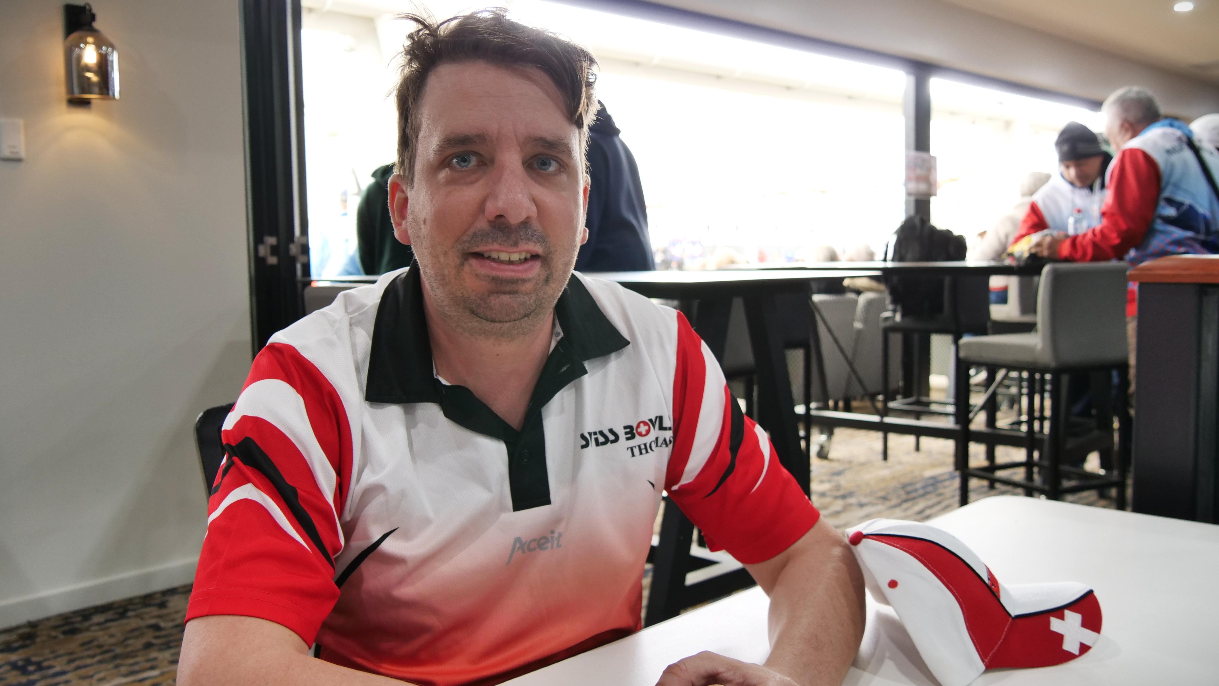 A man in a red and white top sits at a table.