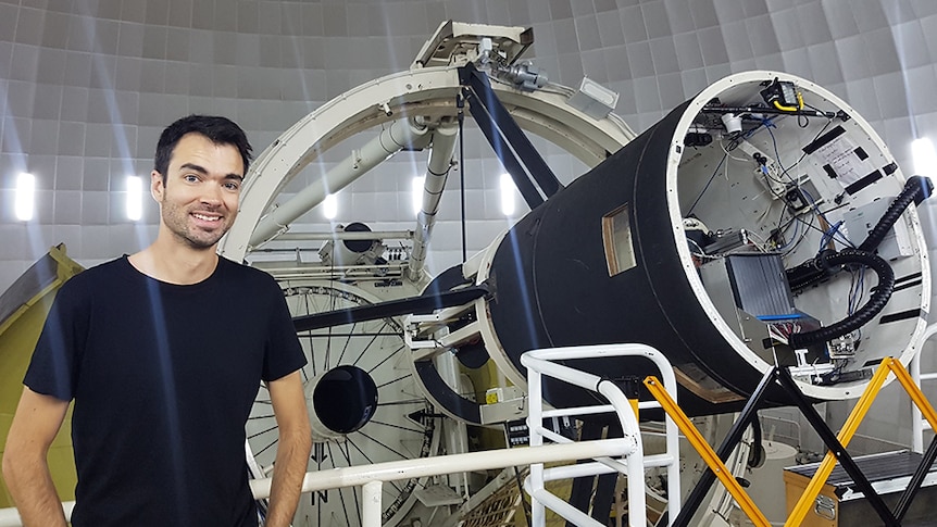 Photo of ANU researcher and engineer Dr James Gilbert standing next to telescope at Mount Stromlo, ANU.