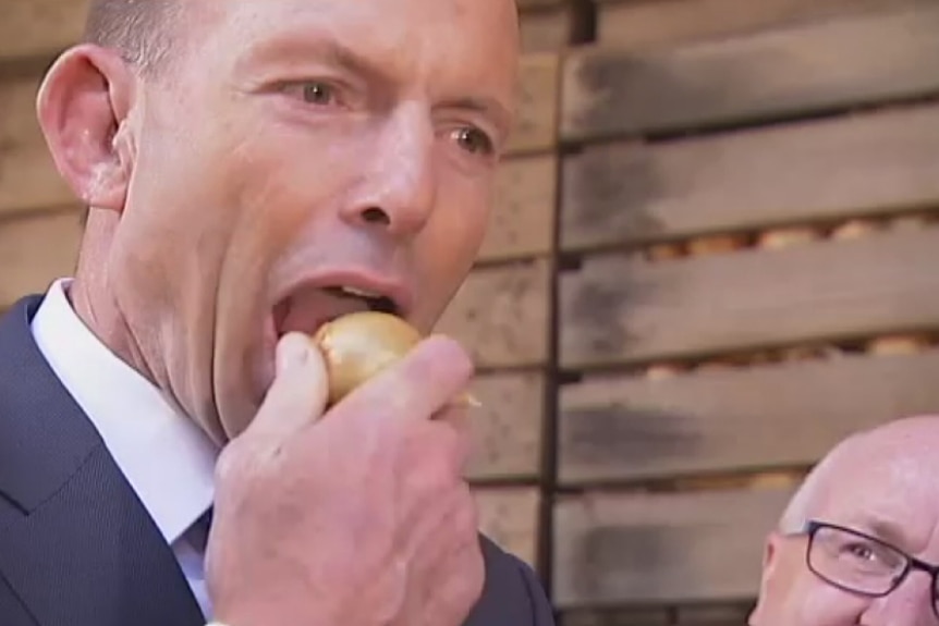 Tony abbot biting into an onion
