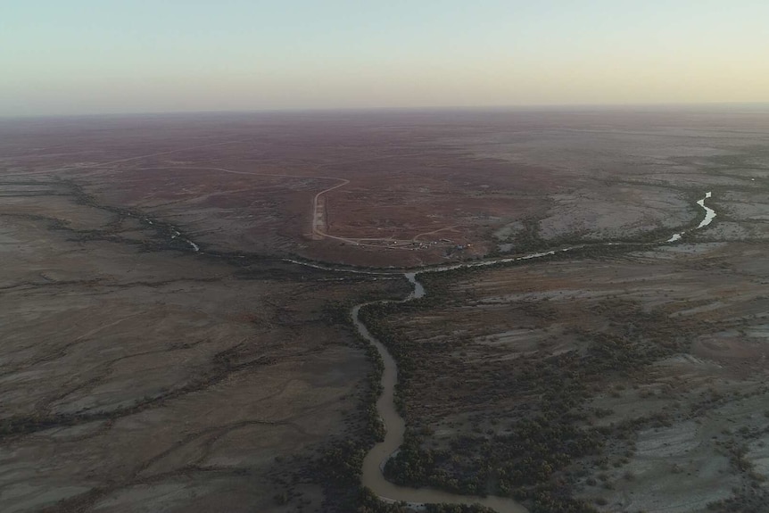An aerial shot of a river snaking through the flat outback.