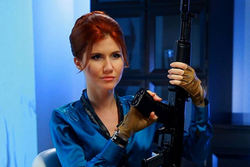 Russian spy Anna Chapman poses with an automatic rifle in a futuristic model shot.