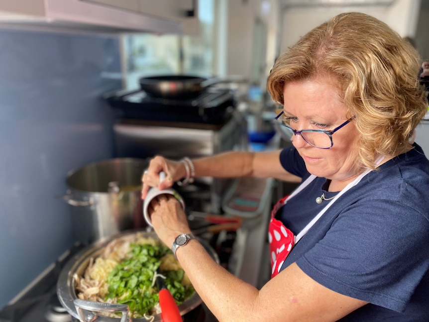 A woman stands over a stove cooking