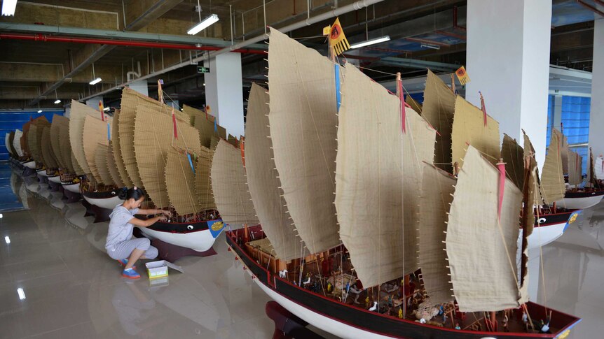 A woman polishes models of the full fleet led by Ming Dynasty eunuch explorer Cheng Ho.