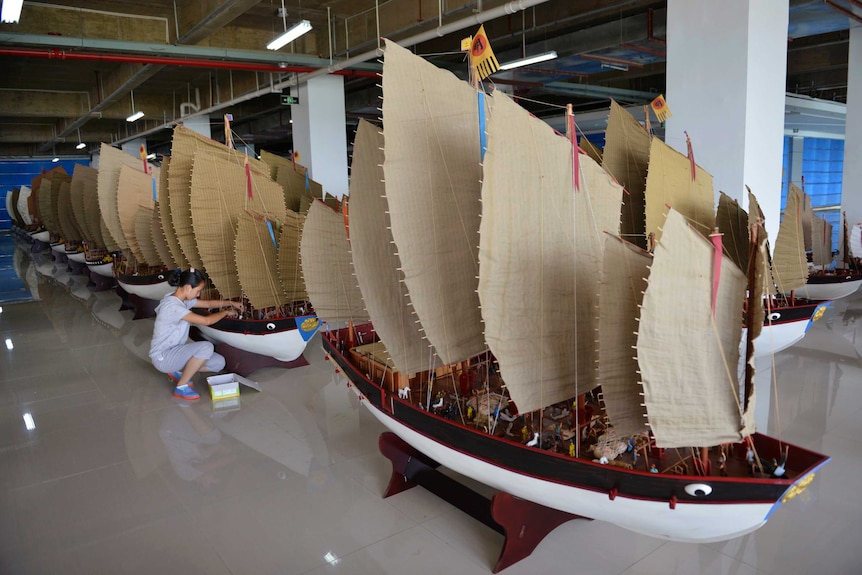 A woman polishes models of the full fleet led by Ming Dynasty eunuch explorer Cheng Ho.