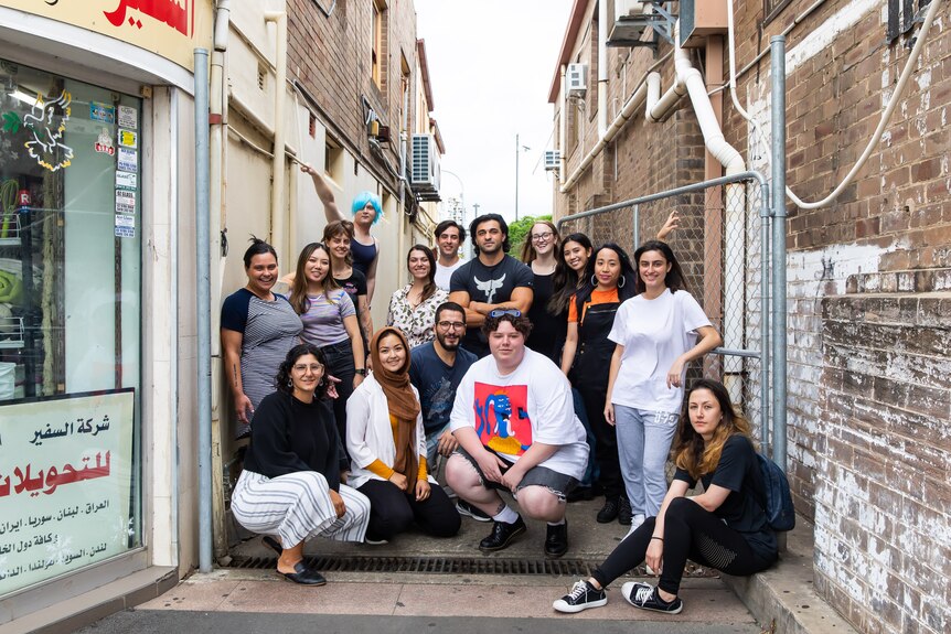 The 2021 Powerhouse Youth Theatre ensemble group pose in an alleyway. 