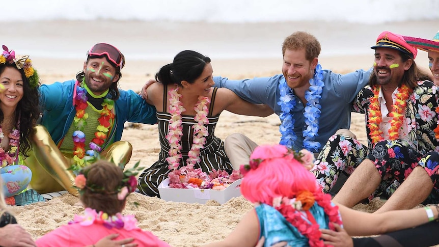 Prince Harry and Meghan Markle sit with the brightly dressed OneWave group on Bondi Beach