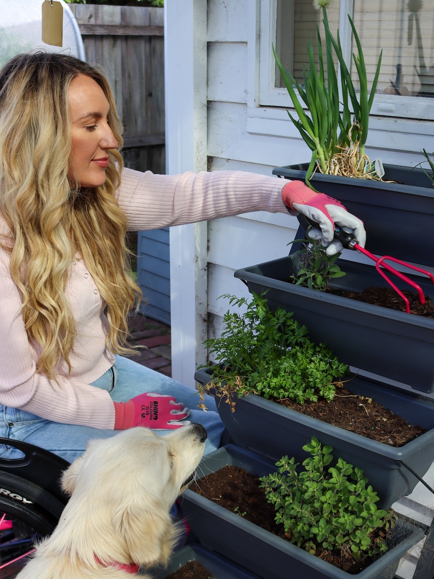 Woman tends to her vertical planters on her balcony, growing food in a rental property.