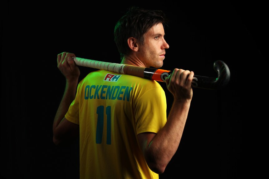 Eddie Ockenden holds a hockey stick over his shoulders and looks to the side in a set up portrait photo.