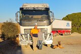 A couple and their dog in front of a truck.