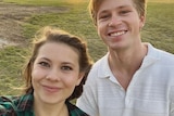 Two young people smiling in a field.