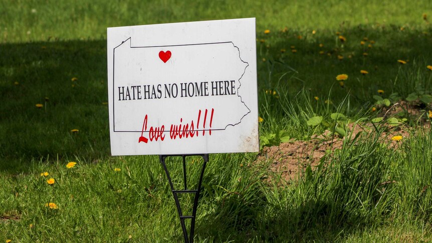 A sign stuck in grass reading "hate has no home here. Love wins"