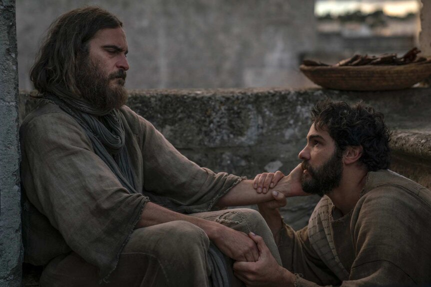 Colour still image from 2018 film Mary Magdalene of Joaquin Phoenix as Jesus Christ clutching the face of Tahar Rahim as Judas.