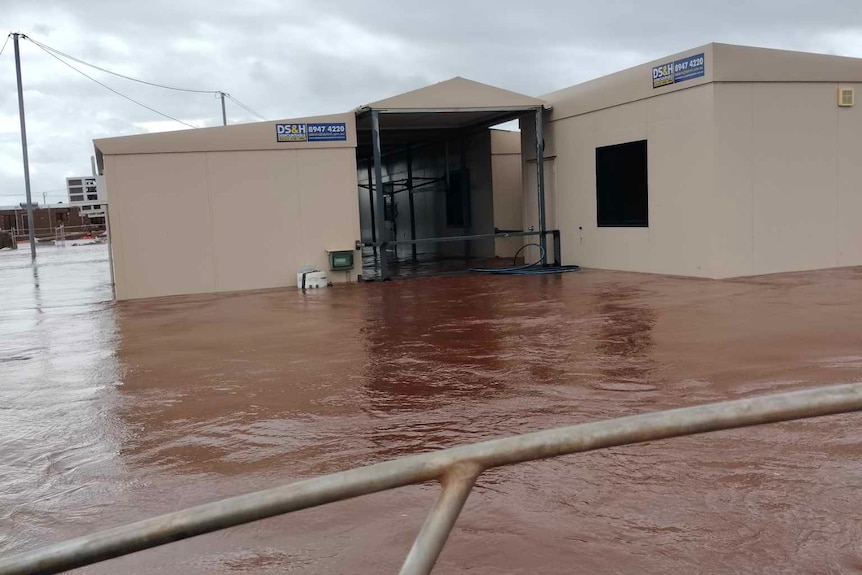 brown floodwaters rising against demountable houses