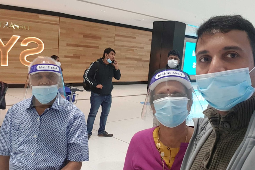 Srihari and his parents at Sydney Airport, wearing face masks and face shields