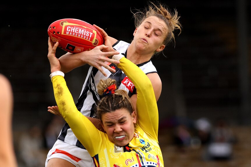 An Adelaide Crows AFLW player attempts to mark in front of a Collingwood opponent.