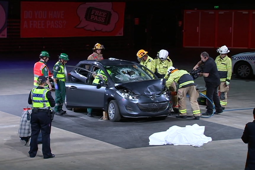 Emergency responders on a stage with a car.
