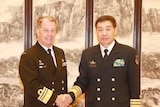 Vice Admiral Tim Barrett and Shen Jinlong, both wearing navy garb, shake hands and look at the camera.