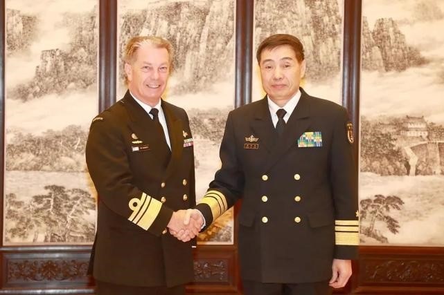 Vice Admiral Tim Barrett and Shen Jinlong, both wearing navy garb, shake hands and look at the camera.