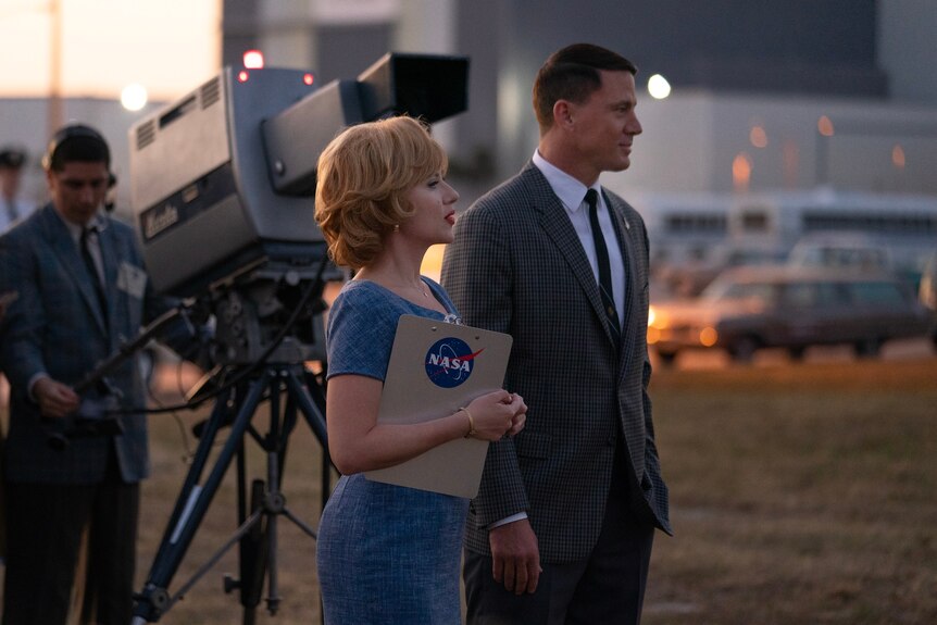 A still from the movie Fly Me to the Moon with Scarlett Johansson and Channing Tatum in 50s clothes, Scarlett holding NASA clipb