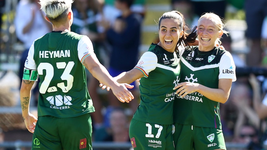 Canberra female football players celebrating.