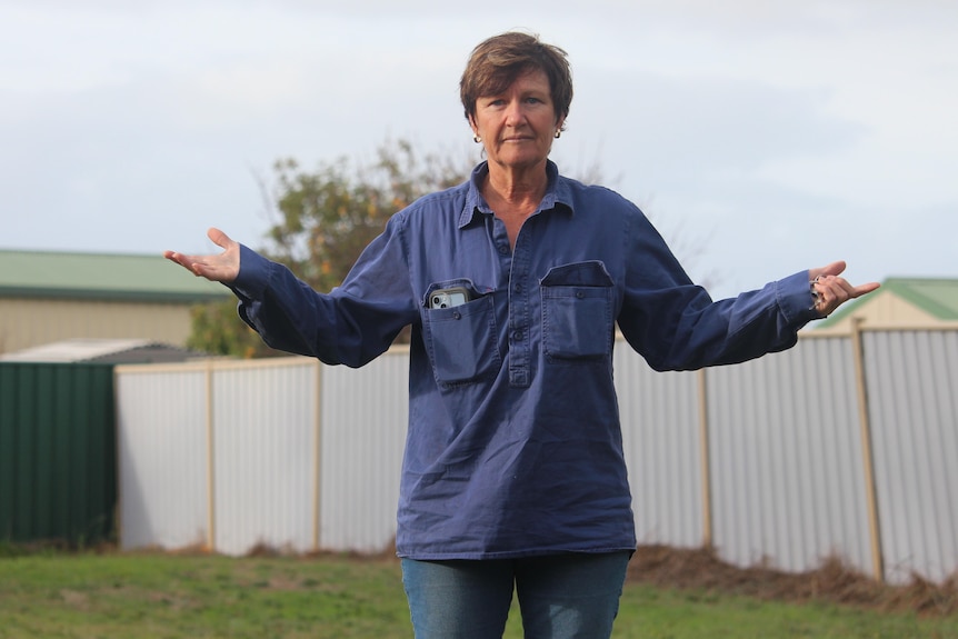 She stands with her hands shrugging towards the sky, on the block bought for the house