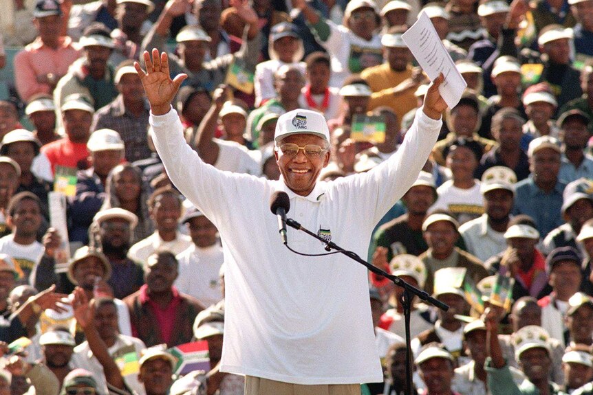 Nelson Mandela waves to African National Congress supporters during the ANC's last election rally on May 30, 1999.