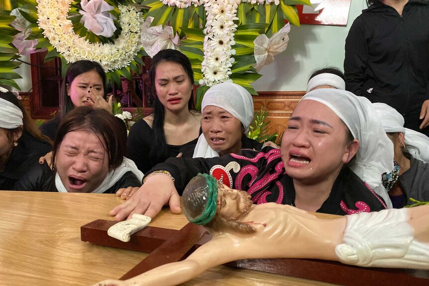 Women mourn next to a casket.