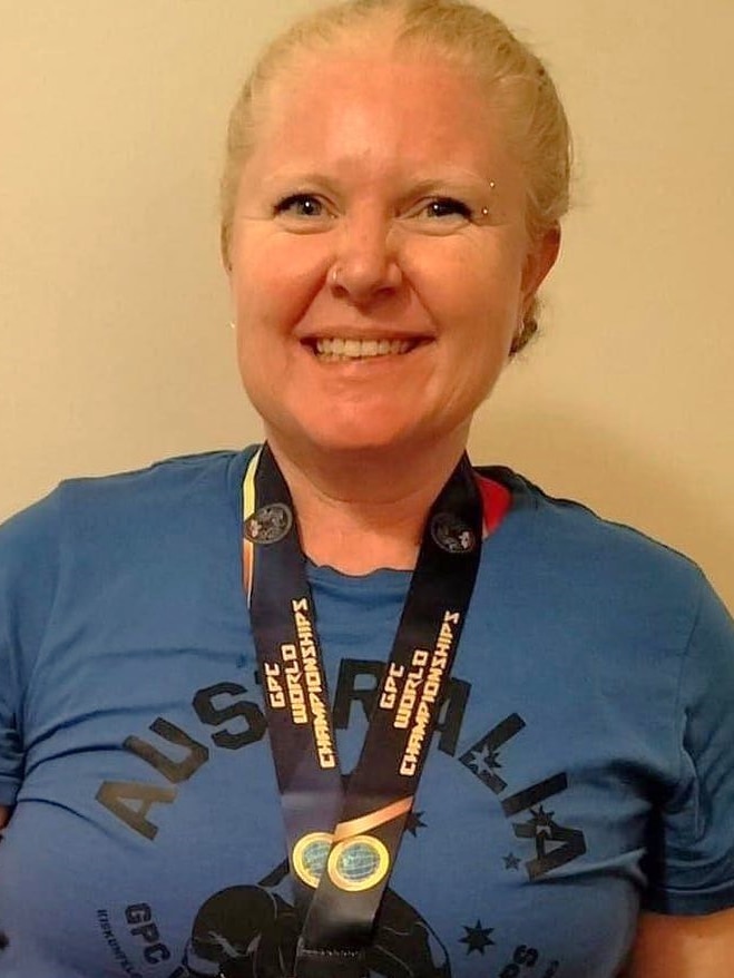 a woman smiling with a gold medal around her neck.