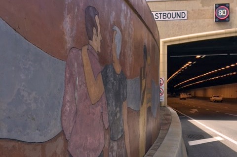 A mural showing people on a retaining wall on the Graham Farmer Freeway, with the Northbridge Tunnel in the background.