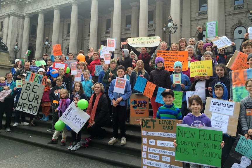 Parents and children stand at Victoria's Parliament house, protesting against changes to homeschool regulations.