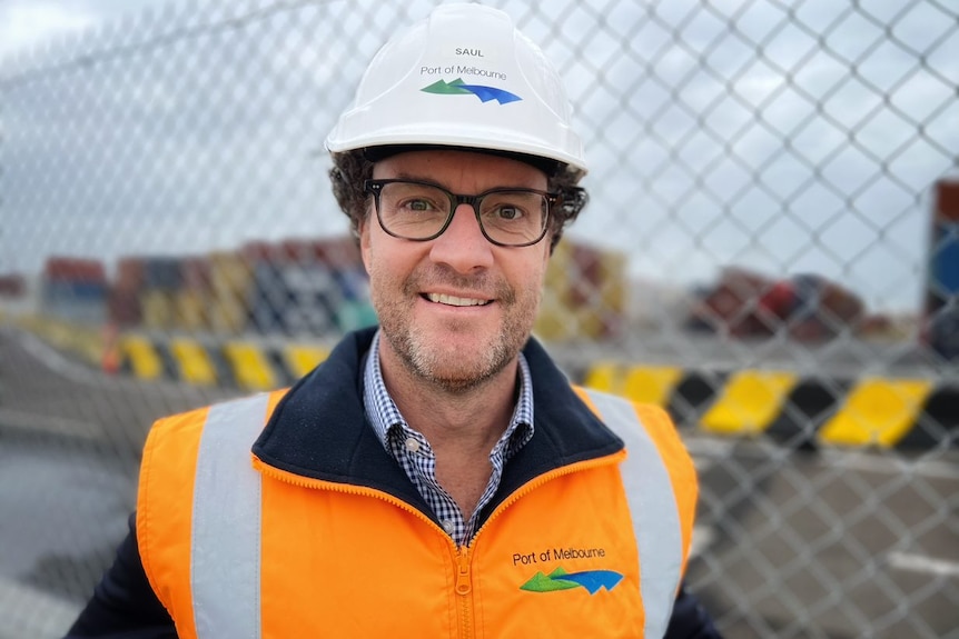 Saul Cannon, wearing a high-vis vest and hard hat, smiles widely.