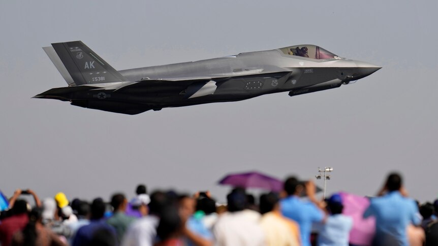 A US F-35 fight jet flies low over a crowd at an airshow.