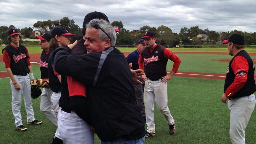 Chris Lane's dad hugs an Essendon baseballer on a baseball field