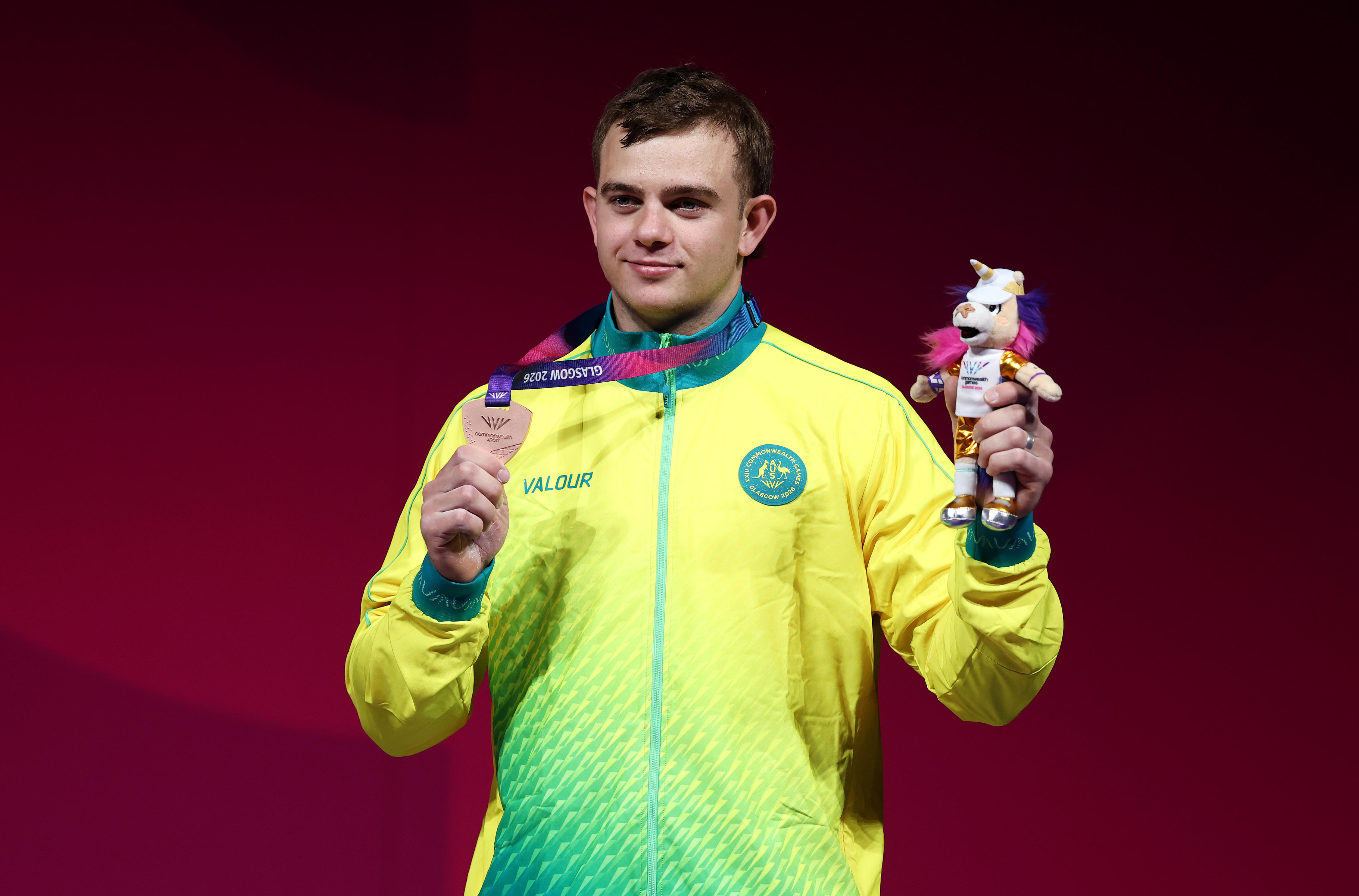 Ollie Saxton holds a bronze medal.
