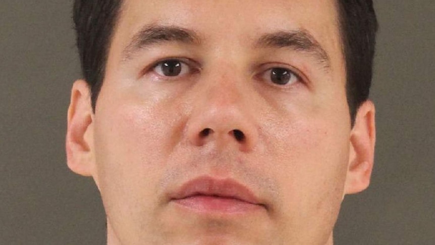 A mug shot of William Husel, looking straight at camera, and standing in front of a brown wall