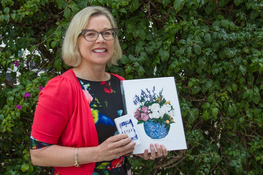 Ally Martell holds the perfume and artwork for the scent.