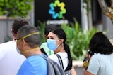 People in face masks stand in a long queue outside the Centrelink office at Southport on Queensland's Gold Coast.