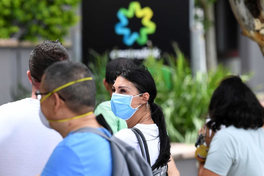 People are seen wearing face masks in a long queue outside the Centrelink office at Southport on Queensland's Gold Coast.