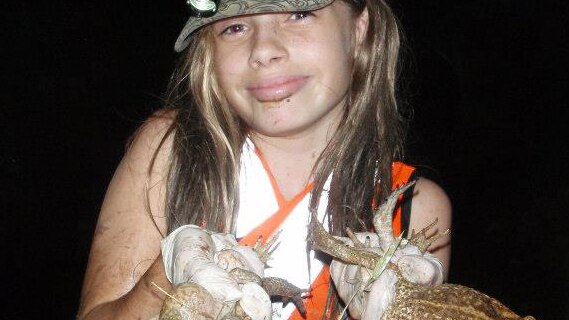 A young girl holds a number of cane toads