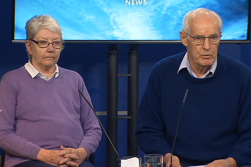 A woman and a man in a police media conference room.