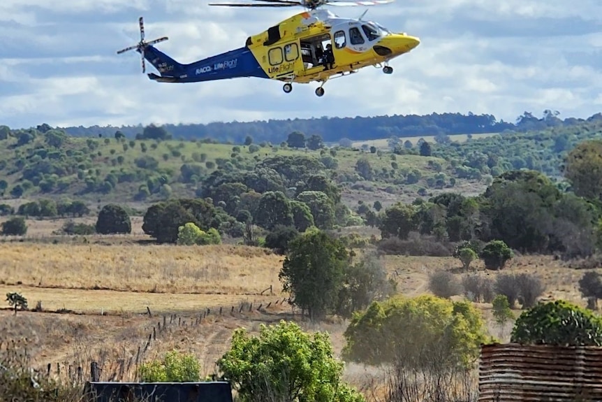 A blue and yellow helicopter in the sky.