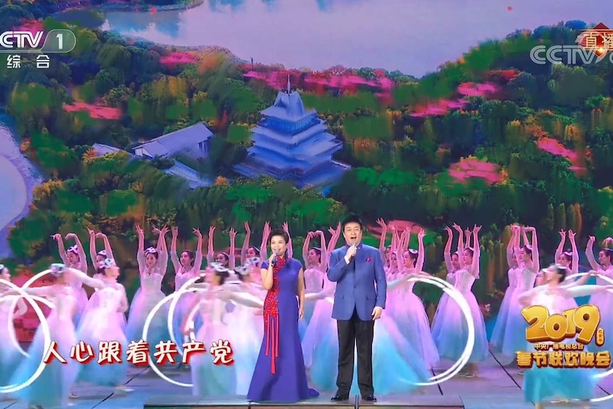 Well-known Chinese singers Ye Zhang and Jihong, left, stand on the stage with a dozen back up dancers.