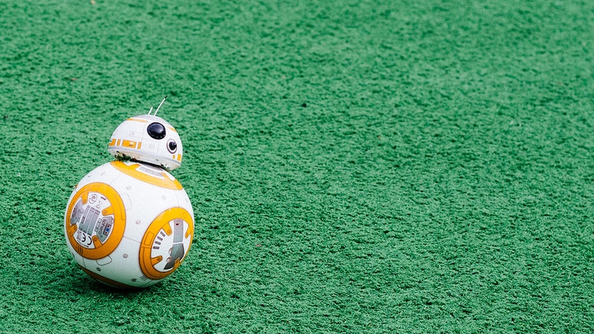 A figurine of the BB8 character from Star Wars sits on green astroturf.