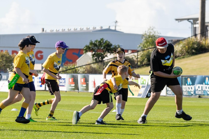 Children in yellow shirts running with a ball on a football field
