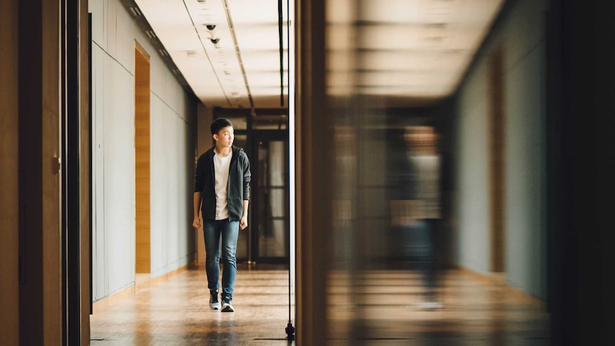 Young boy walks down hallway at school.