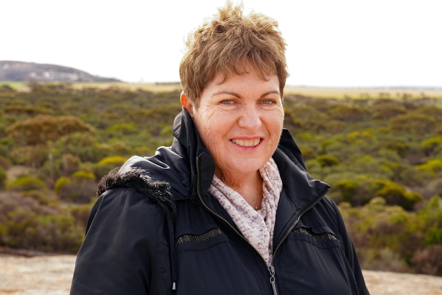 A middle-aged woman smiling outdoors