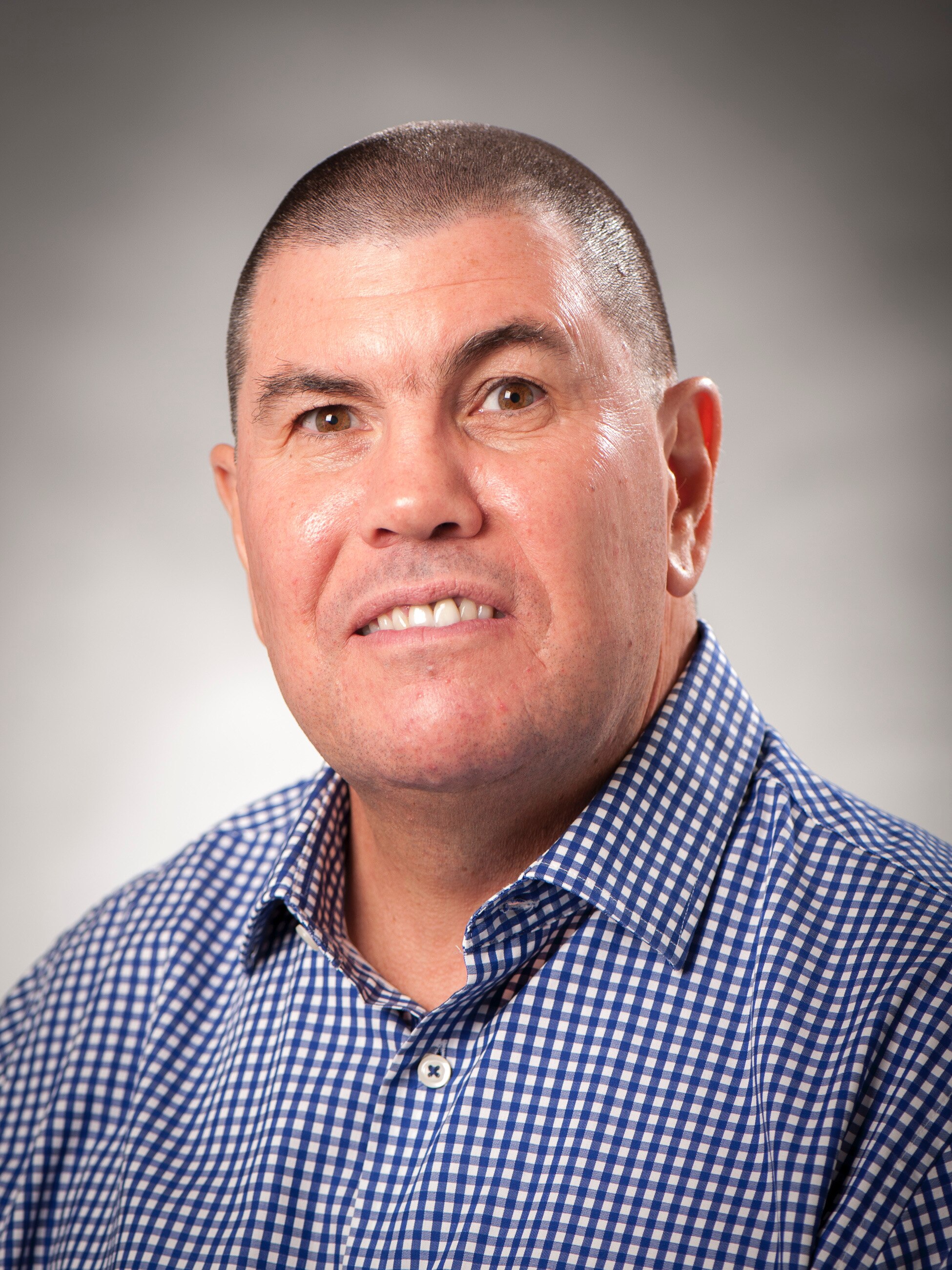Man in blue check shirt smiles for camera 
