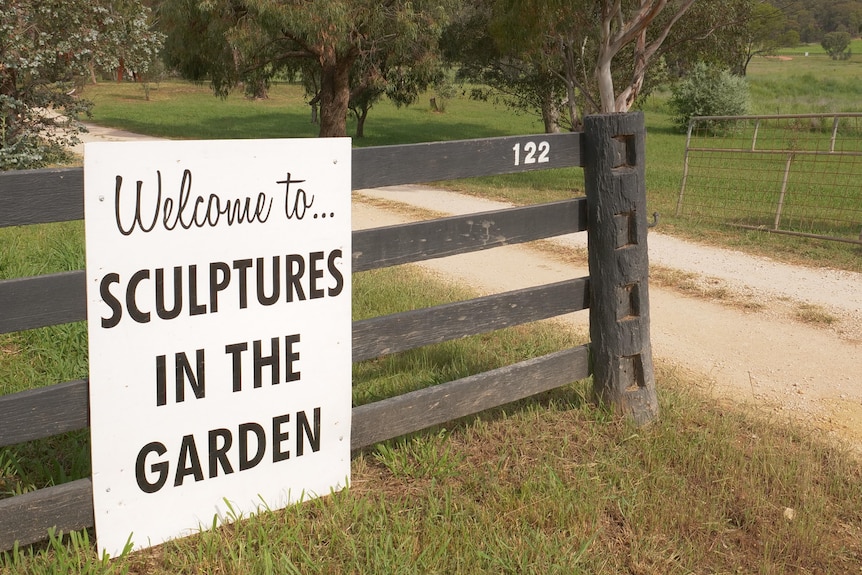 Sign on a gate saying 'welcome to sculptures in the garden'